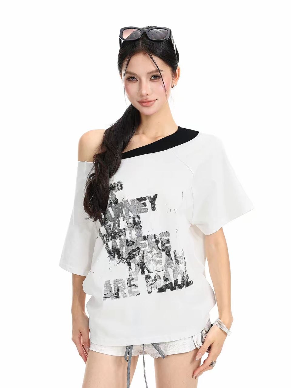 Woman modeling a white graphic T-shirt with black trim and casual denim shorts