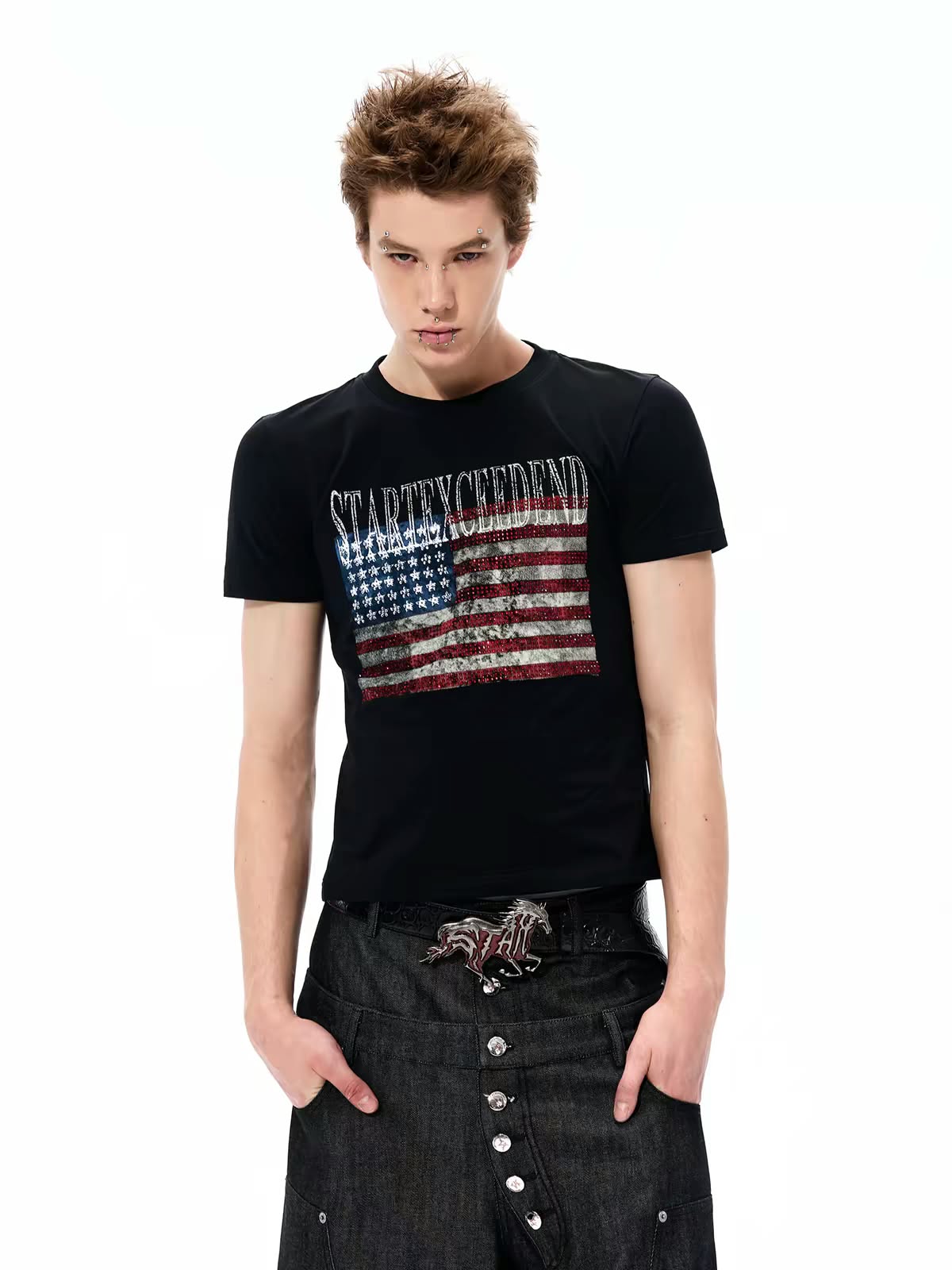 Model wearing a black graphic T-shirt with a distressed American flag design and dark jeans.