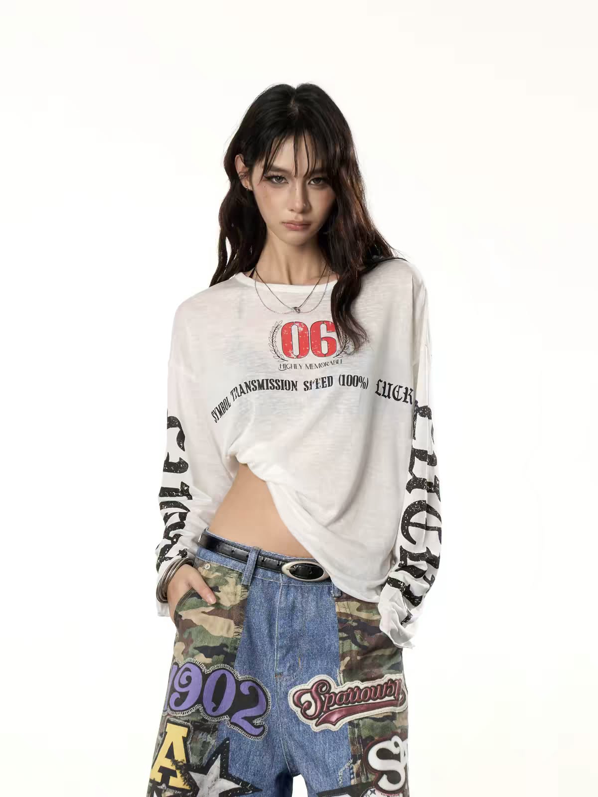 Model wearing a graphic long-sleeve shirt and distressed patchwork jeans.