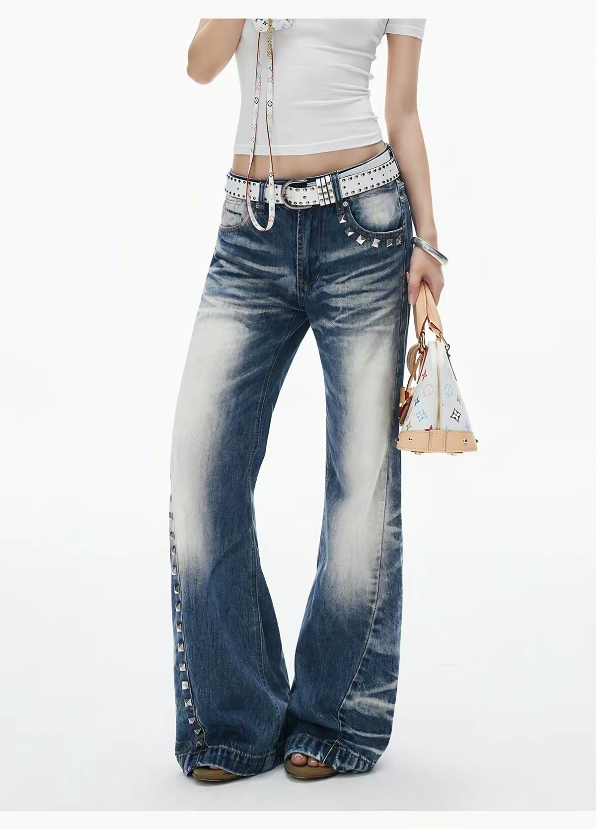 Model wearing wide-leg distressed blue jeans with a white top and accessories