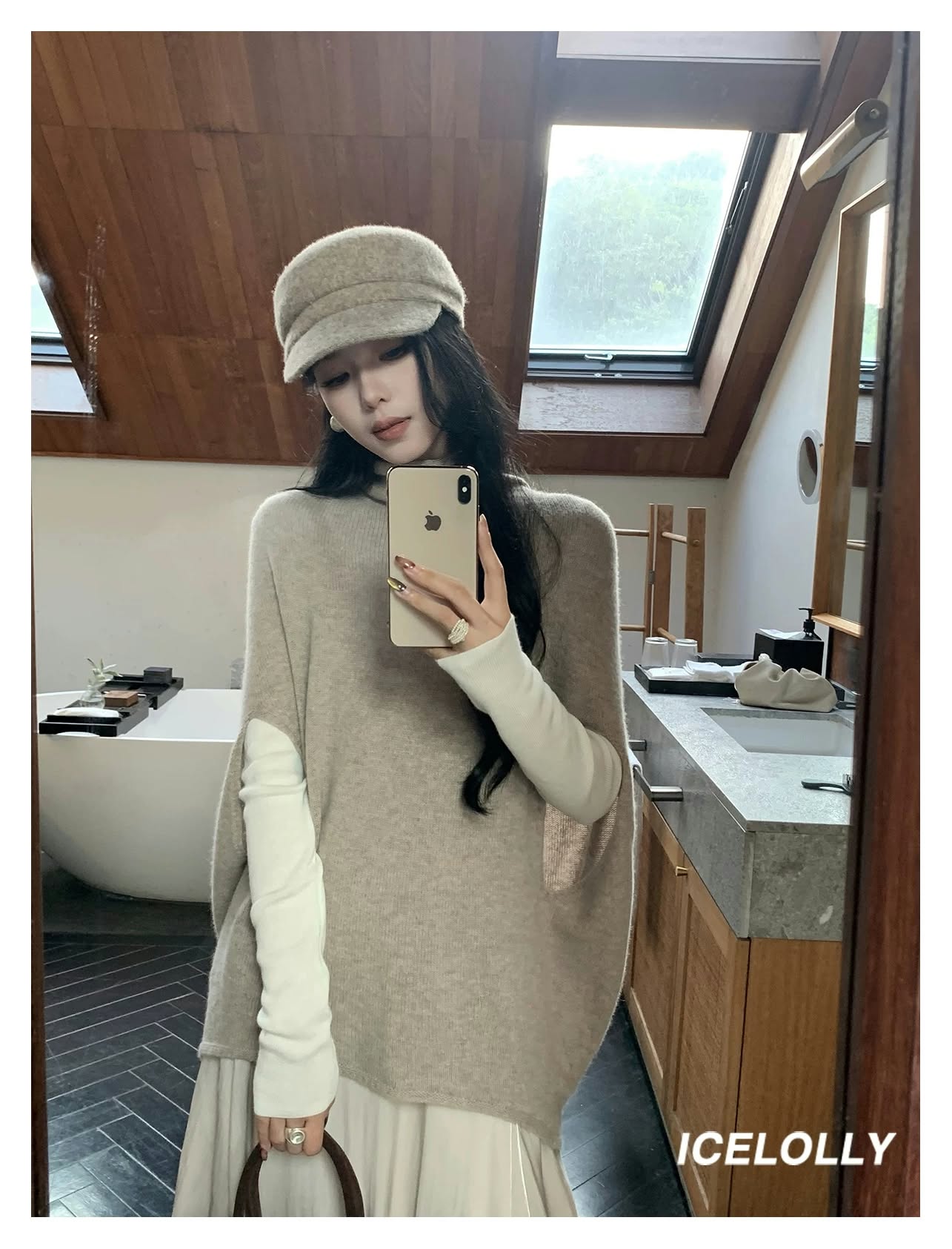 Woman wearing a beige knit sweater vest and matching cap in a mirror selfie.